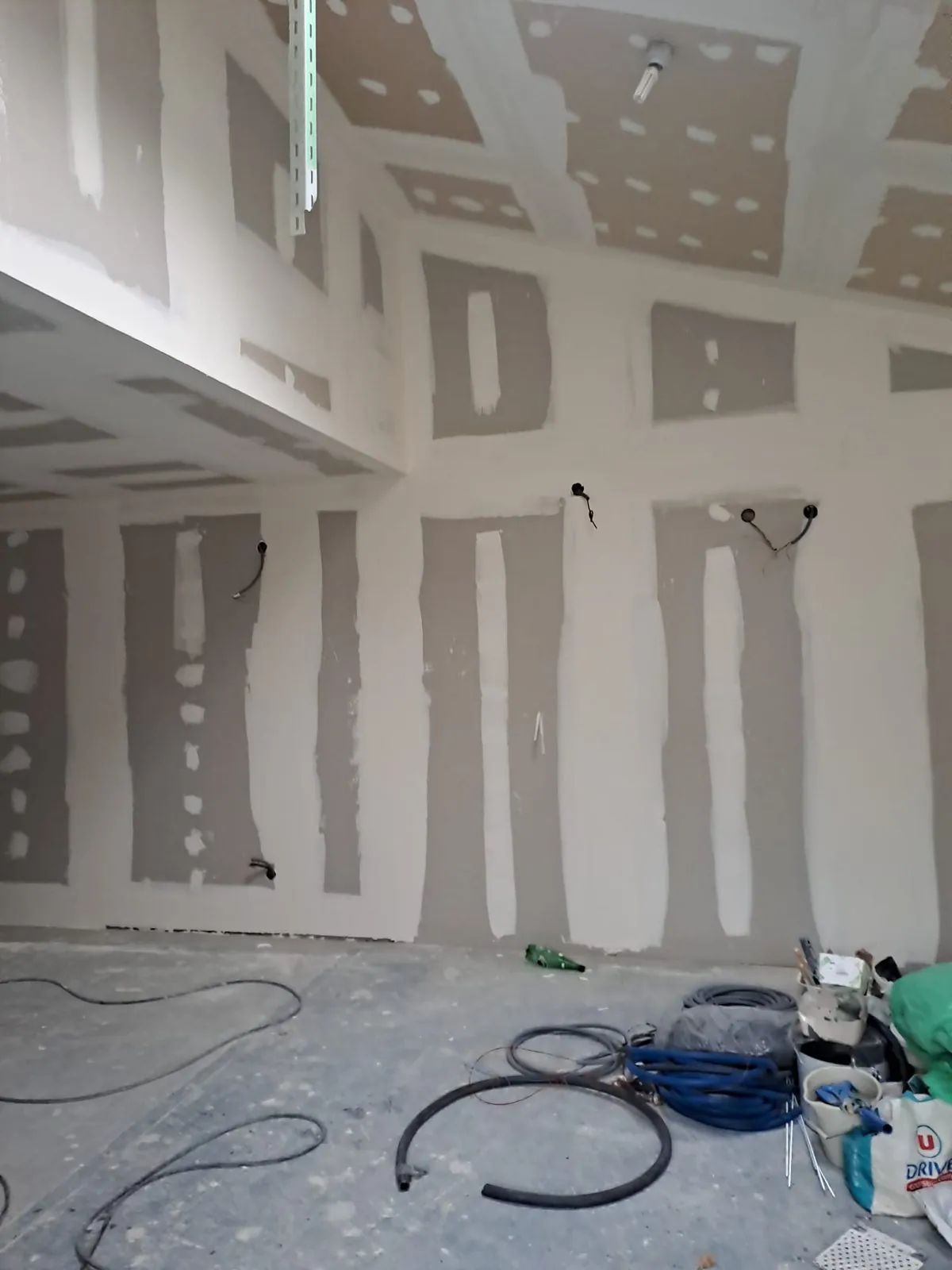 Pièce en chantier, plaques de plâtre posées et joints faits, gaines électriques en attente