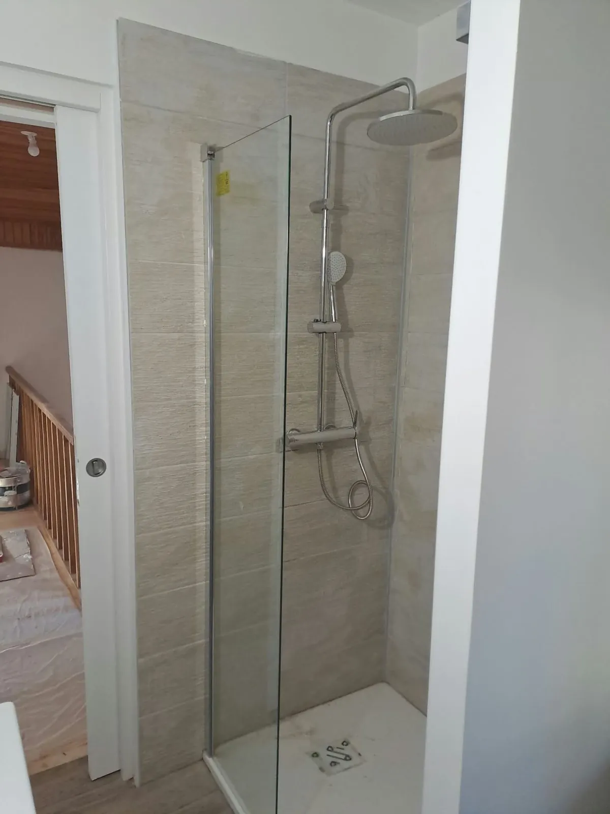 Douche avec paroi vitrée, colonne de douche et faïence beige