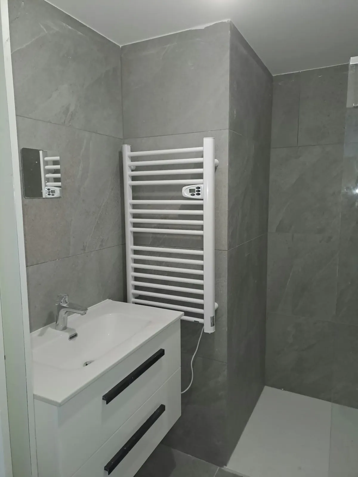 Salle d'eau aux murs gris, meuble vasque blanc et sèche-serviettes
