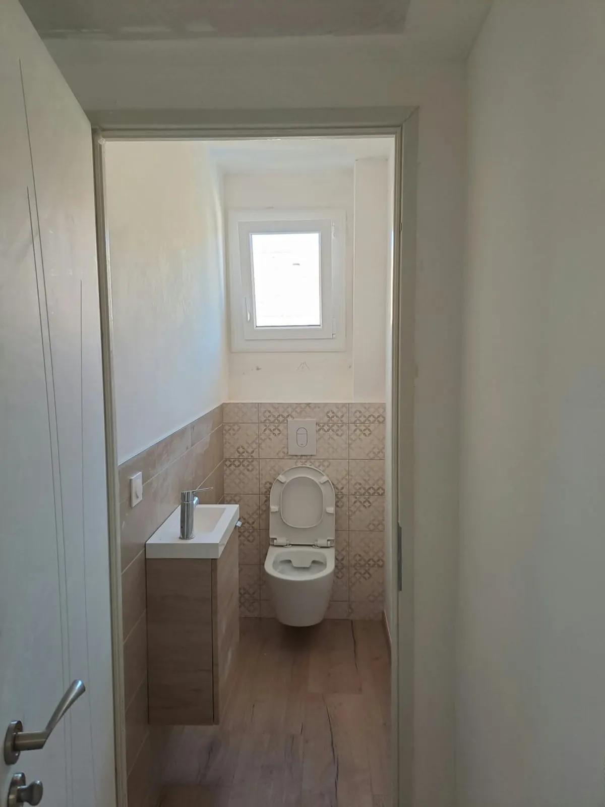 Toilettes avec cuvette suspendue, carreaux décoratifs et lave-mains en bois
